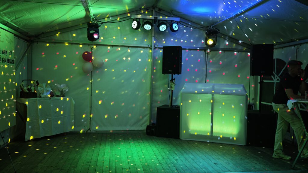 Lautsprecher, DJ-Pult und bunte Lichteffekte in einem Festzelt
